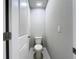 Compact half bathroom with a standard toilet, neutral walls, and a door for privacy at 32451 Limitless Pl, Wesley Chapel, FL 33545