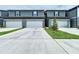 A row of gray two-story townhomes featuring individual garages and a concrete driveway at 32451 Limitless Pl, Wesley Chapel, FL 33545