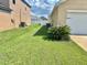 Landscaped side yard with palm trees, green lawn, and white garage door at 3313 San Moise Pl, Plant City, FL 33567