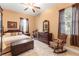 Bright bedroom with ceiling fan, tile floors, rocking chair, dark curtains and decorative dresser at 3402 Melissa Country Way, Lutz, FL 33559