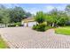 Long brick driveway leading to a home with a three-car garage and landscaped front yard at 3402 Melissa Country Way, Lutz, FL 33559