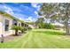 Side view of backyard featuring lush lawn and mature trees near a pond at 4304 Place Le Manes, Lutz, FL 33558