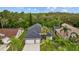 Aerial view of a home with a dark roof, complemented by lush landscaping, palm trees, and a spacious driveway at 4505 Anaconda Dr, New Port Richey, FL 34655