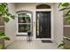 Welcoming front door with sidelight and decorative plants in a cozy, shaded entryway at 4505 Anaconda Dr, New Port Richey, FL 34655