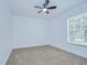 Minimalist bedroom with plush carpet, ceiling fan, and ample natural light from a large window at 4605 W Loughman St, Tampa, FL 33616