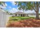 Large, private backyard with a white fence, shade tree, and manicured lawn at 679 Challice Dr, Spring Hill, FL 34609