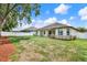 Spacious fenced backyard featuring lush green grass, mature trees and shrubs, perfect for outdoor activities at 679 Challice Dr, Spring Hill, FL 34609