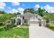 Charming single-story home with a manicured lawn, flowering shrubs, and a three car garage at 679 Challice Dr, Spring Hill, FL 34609