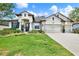 Charming single-story home with a manicured lawn, flowering shrubs, and a three car garage at 679 Challice Dr, Spring Hill, FL 34609