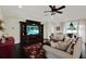 Inviting living room with neutral walls, dark floors, ceiling fan and an entertainment center with a TV at 679 Challice Dr, Spring Hill, FL 34609