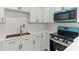 Modern kitchen with stainless steel appliances, white cabinets, quartz countertops, and bronze fixtures at 8009 Somerset Ln, Tampa, FL 33615