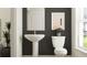 Modern half bathroom featuring a pedestal sink, toilet and decorative accents against a gray accent wall at 9414 Gladsome Dr, Land O Lakes, FL 34637