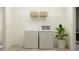 An interior view of the laundry room with a washer and dryer set, shelving and a decorative plant at 9414 Gladsome Dr, Land O Lakes, FL 34637