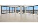 Bright, open living room with tile floors and multiple glass doors with expansive water views at 9425 Blind Pass Rd # 1008, St Pete Beach, FL 33706