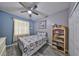 Cozy bedroom with light blue walls, a ceiling fan, a window, and a bookshelf at 11806 Holly Crest Ln, Riverview, FL 33569