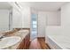 This bathroom features a dual sink vanity, granite countertops, wood-look flooring, and a soaking tub at 11837 Thicket Wood Dr, Riverview, FL 33579