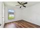 Bright bedroom with hard wood floors, ceiling fan, and a window offering views of the outside at 11837 Thicket Wood Dr, Riverview, FL 33579
