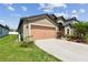 Residential home showcasing a two-car garage, inviting landscaping, and manicured lawn at 11837 Thicket Wood Dr, Riverview, FL 33579