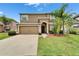 Charming two-story home featuring a well-manicured lawn, arched front door, and a spacious two-car garage at 12316 Streambed Dr, Riverview, FL 33579