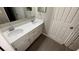 Bathroom vanity with double sinks, white cabinets, quartz countertop, and wood tile flooring at 12804 Millridge Forest St, Tampa, FL 33624