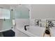 Bright white soaking tub with black fixtures, white marble tile surround, decor, and glass enclosed shower at 13910 Chalk Hill Pl, Riverview, FL 33579