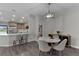 Open concept floorplan with gray wood floors, a marble dining table, and a modern kitchen area with bar stool seating at 13910 Chalk Hill Pl, Riverview, FL 33579