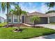 Beautiful home featuring a lush green lawn, mature palm trees, and a two-car garage at 13910 Chalk Hill Pl, Riverview, FL 33579