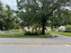 Charming single-story home with a well-manicured lawn, red door, and mature trees at 15034 Lake Magdalene Blvd, Tampa, FL 33618
