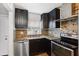 Updated kitchen with black cabinetry, granite countertops, stainless steel appliances and tile backsplash at 2834 Somerset Park Dr, Tampa, FL 33613