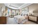 Comfortable main bedroom with soft lighting, tray ceiling, neutral colors, and decorative pictures at 29472 Velletri Ln, Wesley Chapel, FL 33543