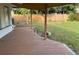 Covered back porch features a wooden deck and view of the green, fenced backyard at 3118 Adrian Ave, Largo, FL 33774