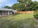 Wide view of the green backyard, featuring a wood fence and covered patio at 3118 Adrian Ave, Largo, FL 33774
