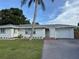 Charming single-story home with a well-maintained lawn, a palm tree and a driveway at 3118 Adrian Ave, Largo, FL 33774