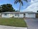 Charming single-story home with a well-maintained lawn, a palm tree and a driveway at 3118 Adrian Ave, Largo, FL 33774