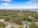 Beautiful aerial view shows a blue home amongst lush greenery near calm water with cloudy blue skies at 320 Broadway, Dunedin, FL 34698