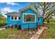 Exterior shot shows the rear of a blue home with a fenced yard and brick foundation accents at 320 Broadway, Dunedin, FL 34698