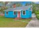A quaint blue house with a bright pink door and brick accents offers charm and curb appeal at 320 Broadway, Dunedin, FL 34698
