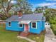 Attractive blue home with gray roof, pink door, and detached garage, offering curb appeal at 320 Broadway, Dunedin, FL 34698