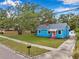 Attractive blue home with a brick chimney, a pink door, and mature trees shading the property at 320 Broadway, Dunedin, FL 34698