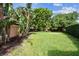 Expansive backyard with lush green lawn, tropical foliage, and mature trees at 3308 Landing Pl, Palm Harbor, FL 34684