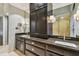 Bathroom featuring dual sinks, granite counters, dark wood cabinets, and a large mirror at 3308 Landing Pl, Palm Harbor, FL 34684