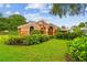 Beautifully landscaped front yard featuring lush green lawn, mature trees and colorful plants at 3308 Landing Pl, Palm Harbor, FL 34684