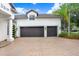 Spacious two-car garage with a brick paver driveway and well-maintained landscaping at 3519 Old Course Ln, Valrico, FL 33596