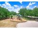 Community playground with slides and climbing structures surrounded by mature trees and grassy areas at 3519 Old Course Ln, Valrico, FL 33596