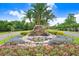 Beautiful water feature with flowers and palm trees enhancing the community entrance, under a bright sunny sky at 3519 Old Course Ln, Valrico, FL 33596