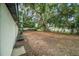 Large backyard featuring mature trees, partial fencing, and a small back porch at 3812 W Rogers Ave, Tampa, FL 33611