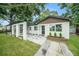 Charming single-story home with white exterior, stylish landscaping and a welcoming pergola-covered entry at 3812 W Rogers Ave, Tampa, FL 33611