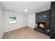 Cozy living room with black brick fireplace, new flooring, and natural light from the window at 3812 W Rogers Ave, Tampa, FL 33611
