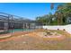 View of backyard with a screened pool, a fire pit, and mature trees and landscaping at 4012 N Munro St, Tampa, FL 33603