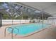A screened-in pool features a patio surround and white fencing with trees in the background at 4012 N Munro St, Tampa, FL 33603
